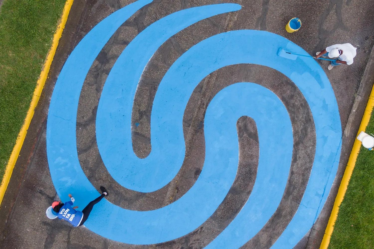 Personas pintan en una calle el logo de Ciudad del Saber