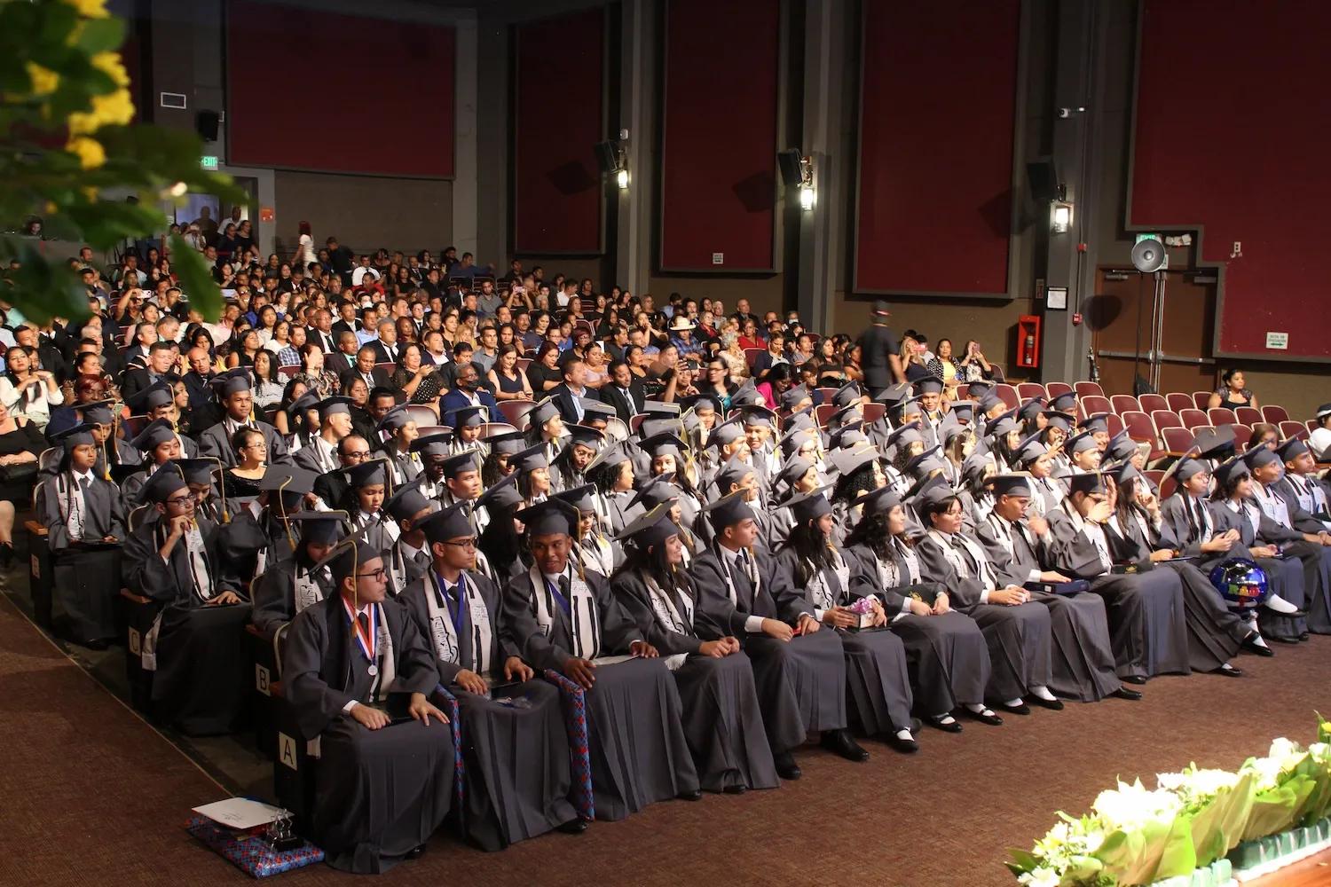 Diferentes alumnos en un auditorio en su ceremonia de graduación