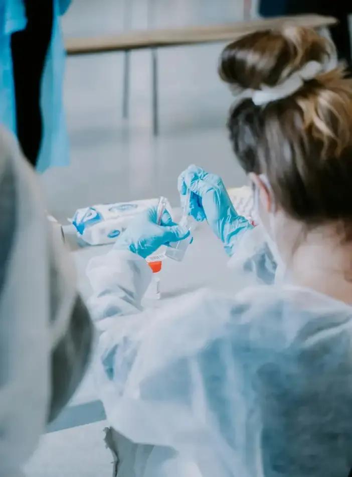 Profesional femenina en bata de laboratorio, llevando a cabo experimentos y análisis en un laboratorio.